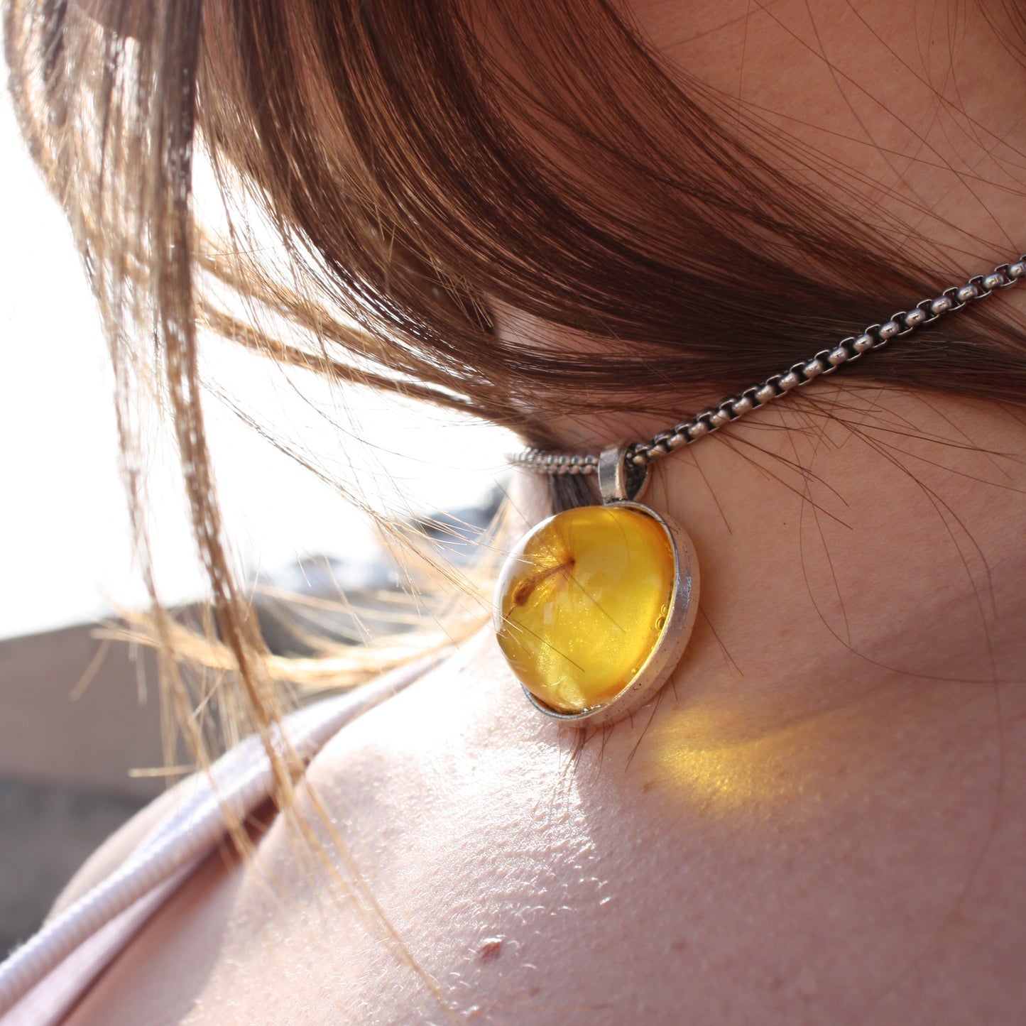PENDANT WITH A FLYING SEED INSIDE AMBER RESIN.