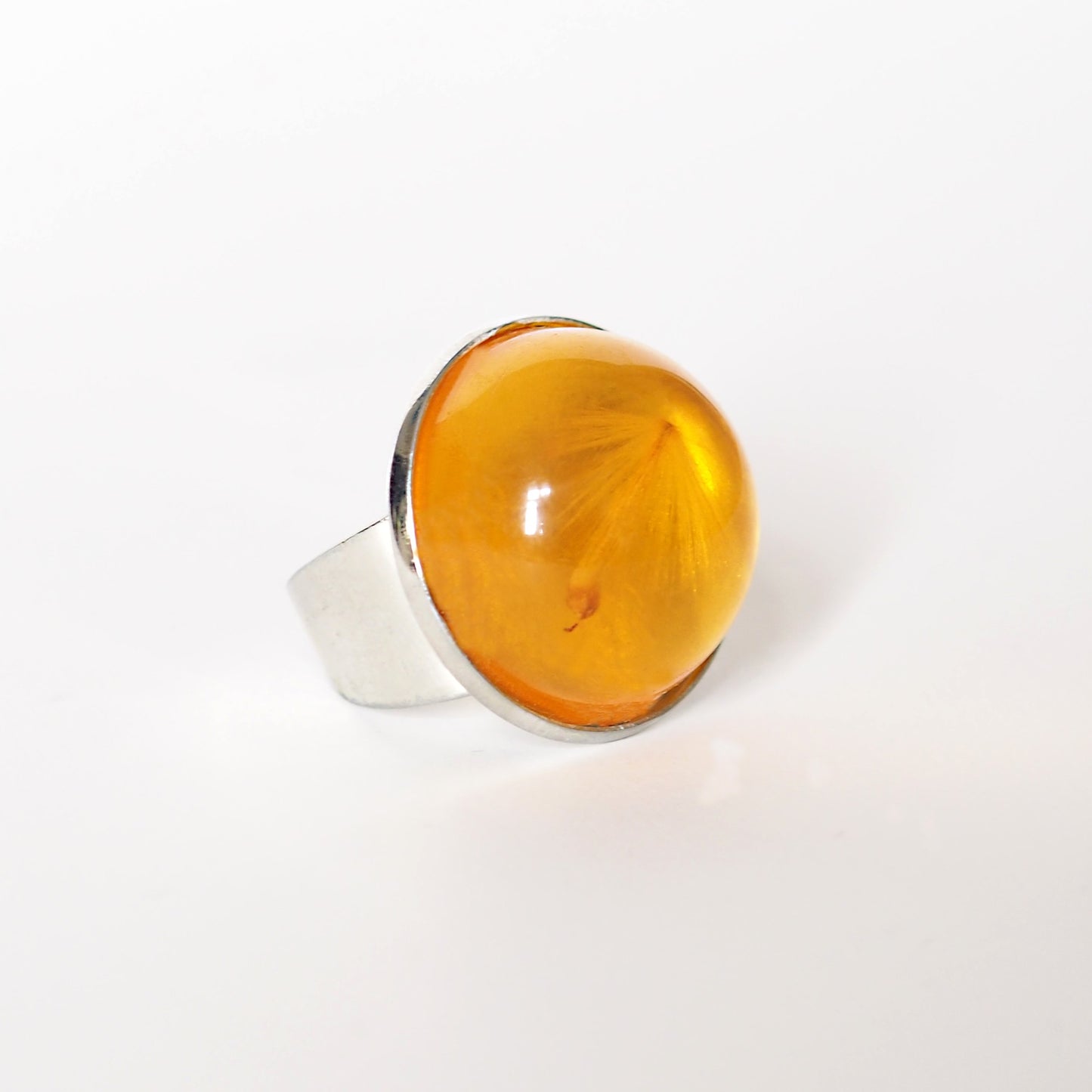 RING WITH A FLYING SEED INSIDE AMBER RESIN.