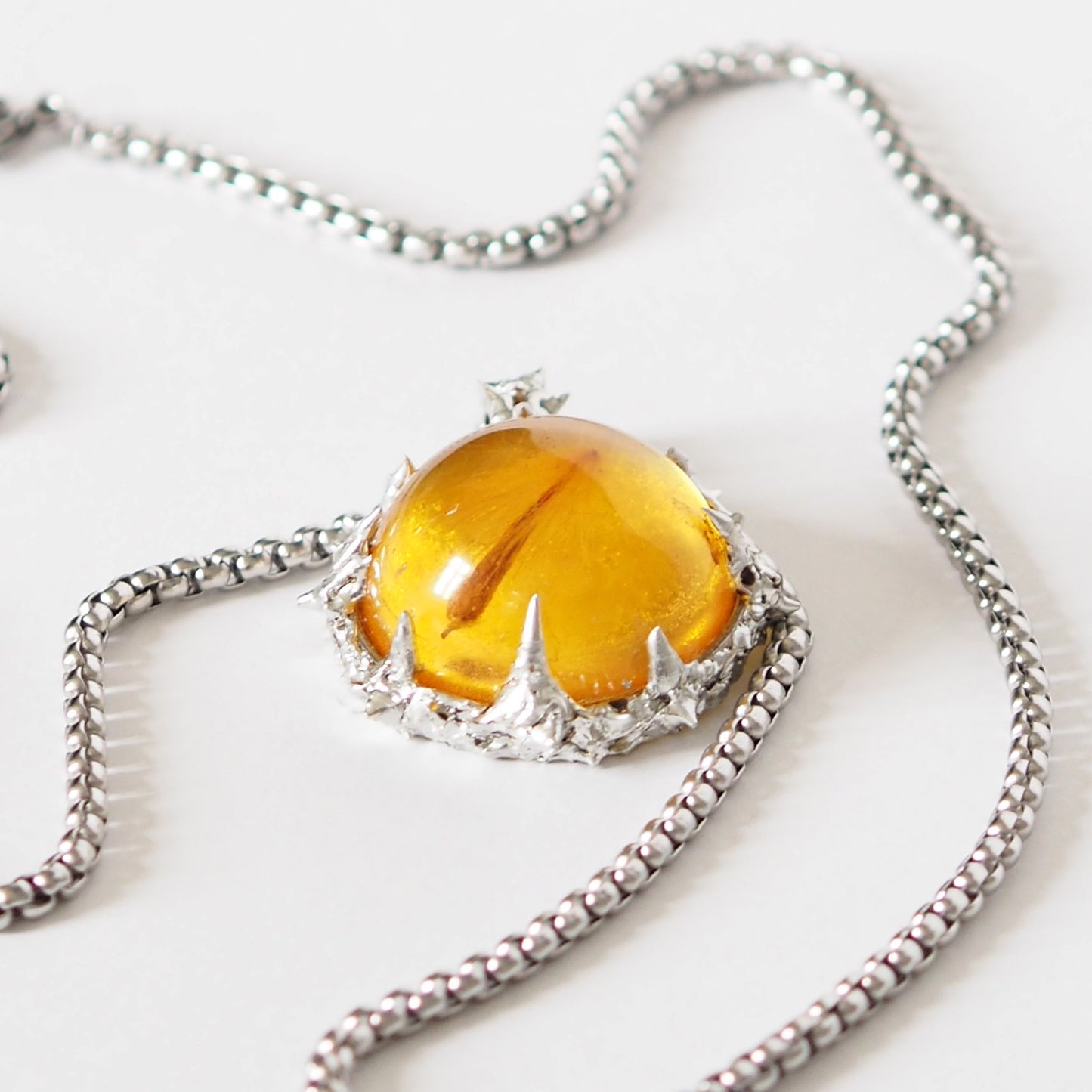 PENDANT WITH A SEED IN AMBER RESIN (HAND-CRAFTED).