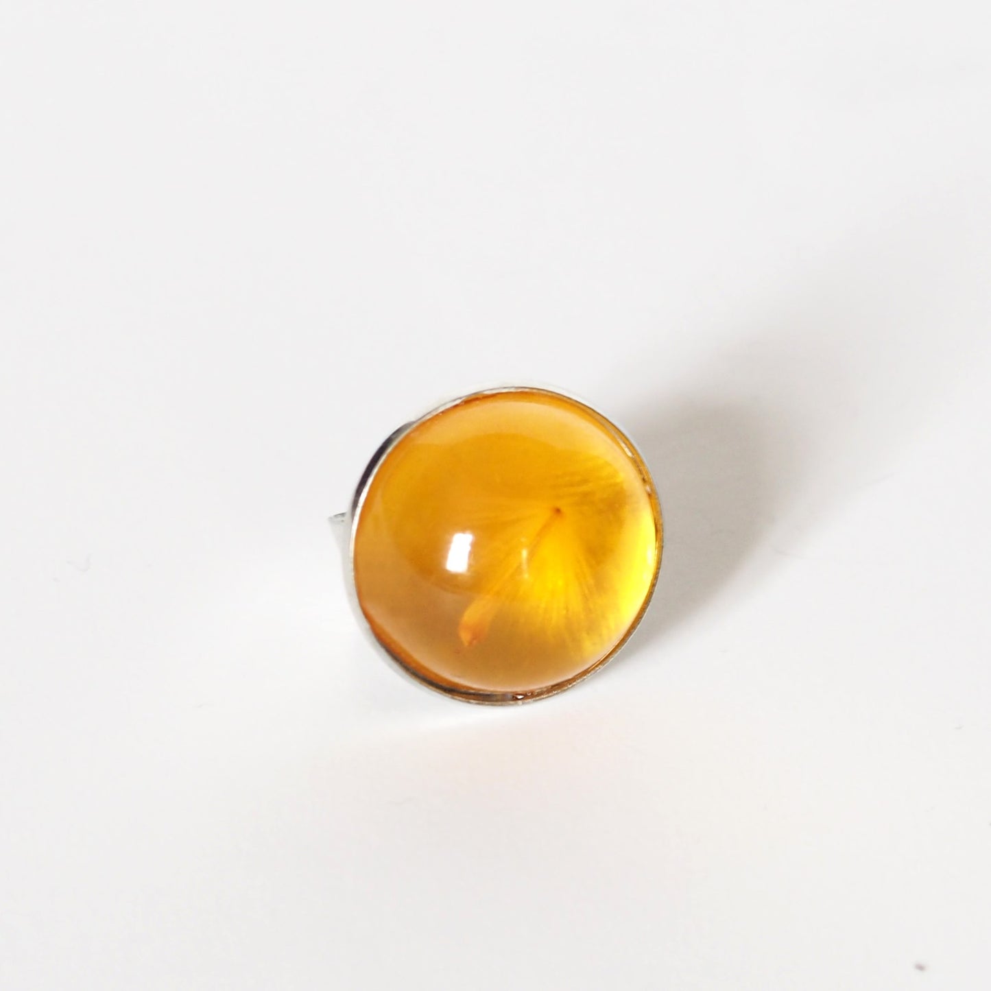 RING WITH A FLYING SEED INSIDE AMBER RESIN.