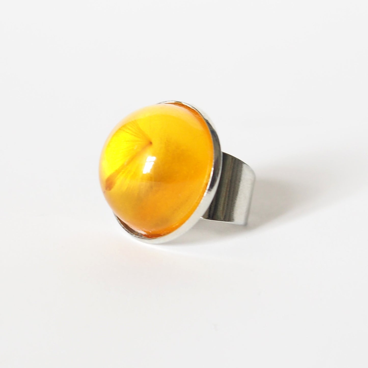 RING WITH A FLYING SEED INSIDE AMBER RESIN.