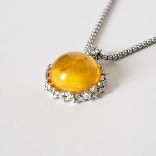 PENDANT WITH A FLYING SEED INSIDE AMBER RESIN.