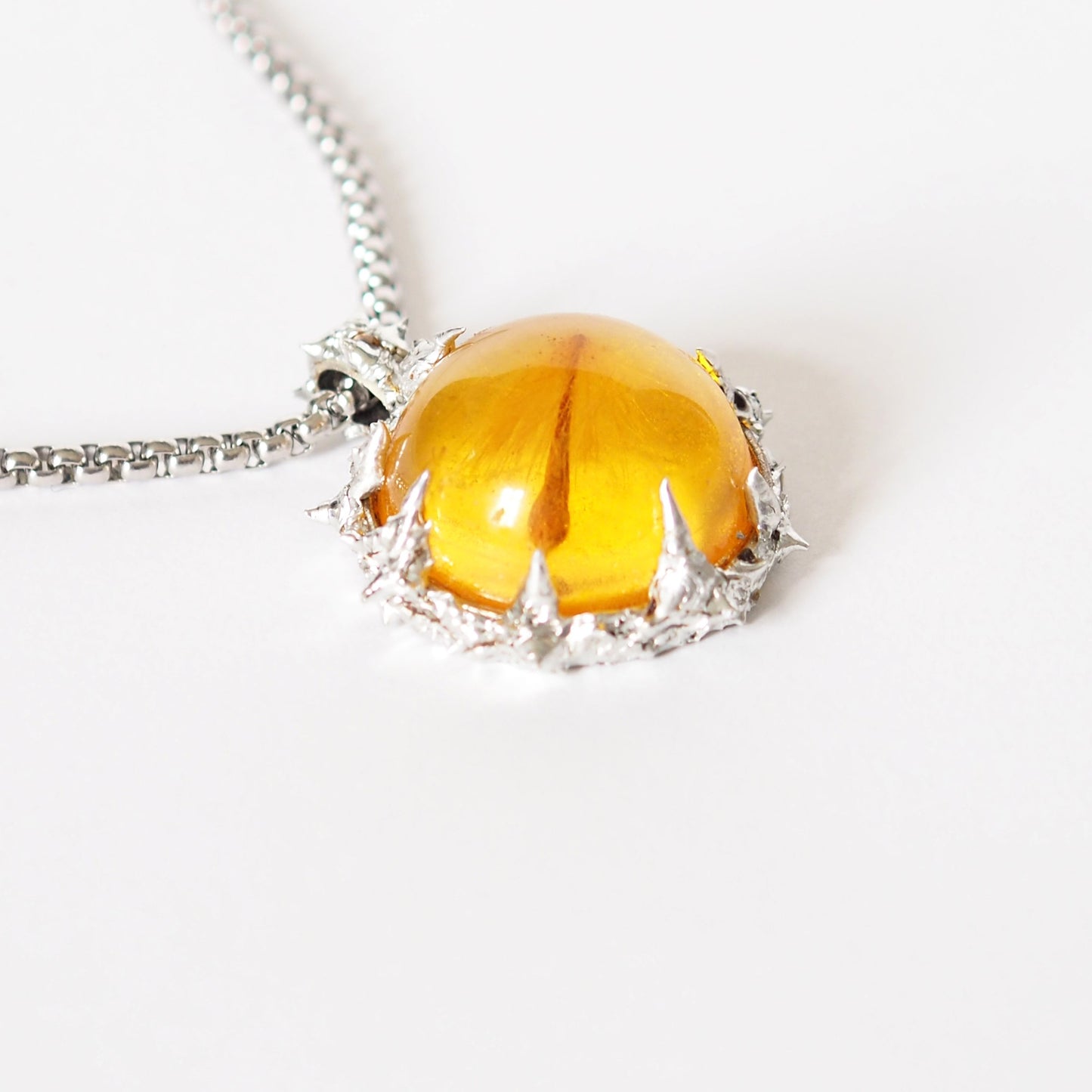 PENDANT WITH A SEED IN AMBER RESIN (HAND-CRAFTED).